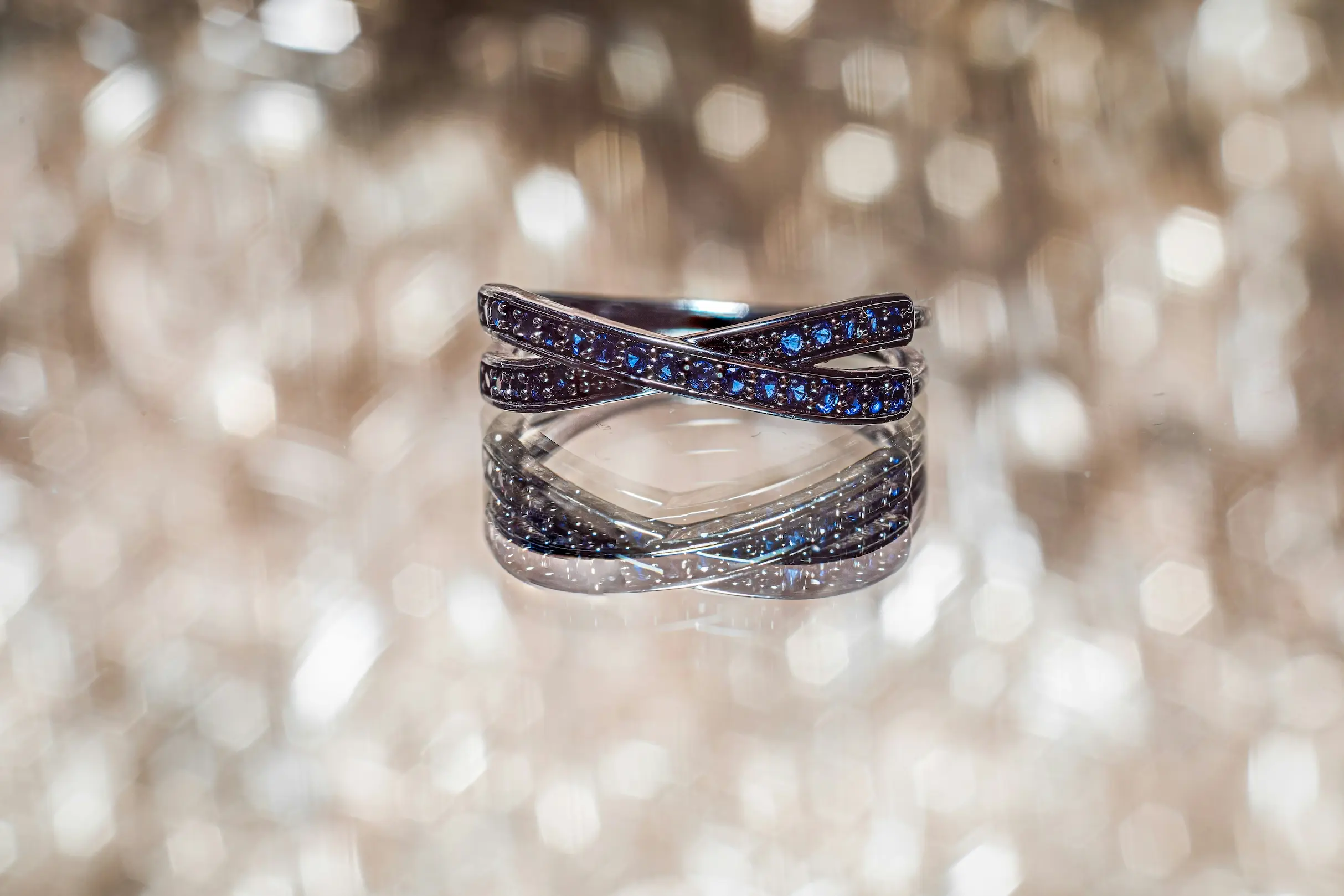 Bespoke fine luxury gemstone ring with brilliant blue diamonds on a reflective shimmering background for a South African designer boutique.